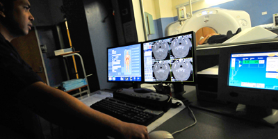 Male radiologic technician operating a CT scanner